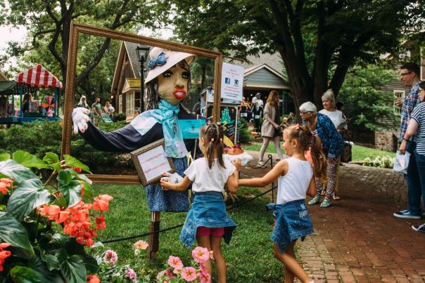 Little girls on an outdoor pathway at Peddler's Village in Lahaska, PA standing in front of a unique scarecrow