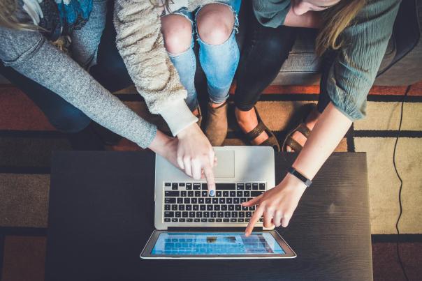 Three people plan a trip using a laptop