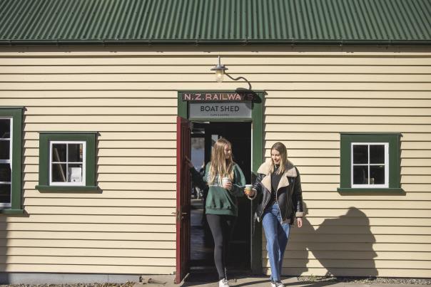 Two people walking out of the Boat Shed Café with keep cups