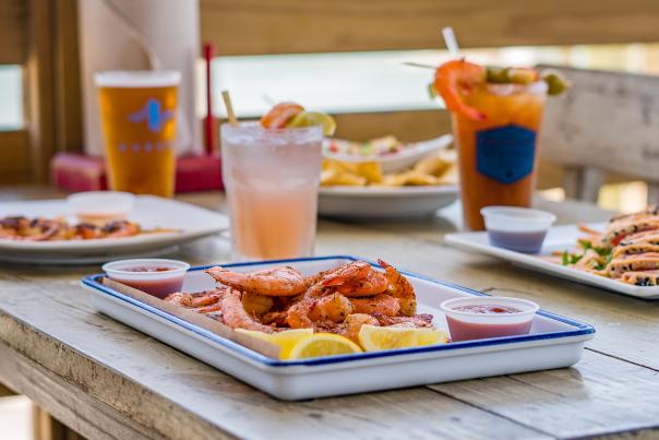A plate of seafood on a table outside on a deck overlooking the water.