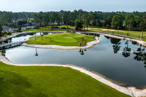 a golf course green at Brunswick Plantation & Golf Resort surrounded by a water trap pond