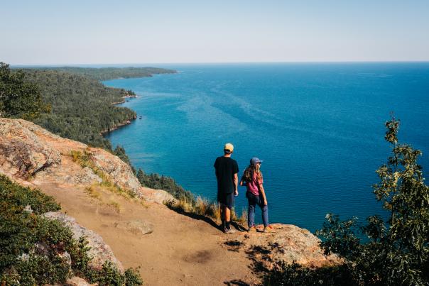 A couple standing at the edge of rocky outcropping overlooking Lake Superior, in the Upper Peninsula of Michigan