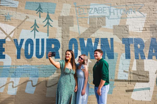 Three friends posing in front of a mural located in Downtown Elizabethtown, KY