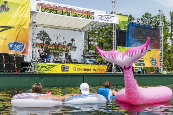 4 people in a lake on floats watching live music