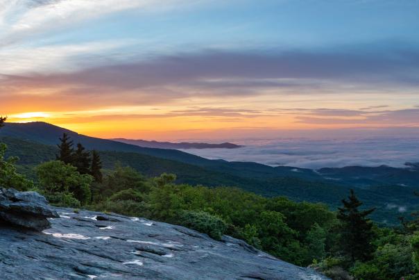 A striking panoramic view of the sun rising over the Appalachian Mountains on the left, with some cloud inversion on the right.