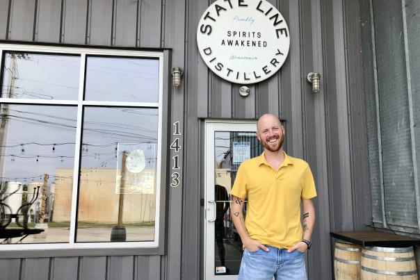 A man poses in front of State Line Distillery