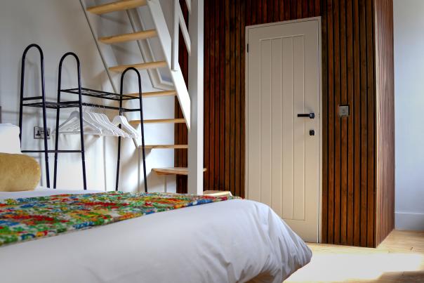A hotel room with a double bed, clothing rail and interior staircase at the Hotel Sleep in Worthing