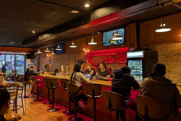 Group of people sitting at a Jollof Afro-Caribbean Lounge, enjoying drinks and conversation.