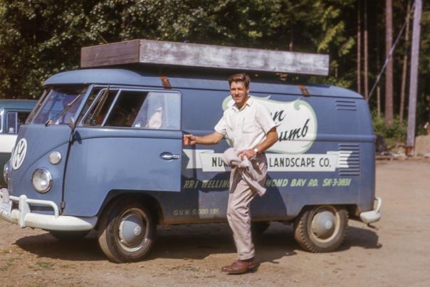 An old photo of a man entering a Volkswagen bus.