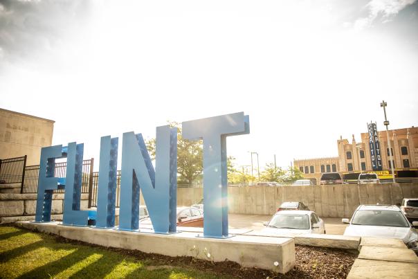 The blue Flint sign with The Capitol Theatre in the background in downtown Flint, Michigan.