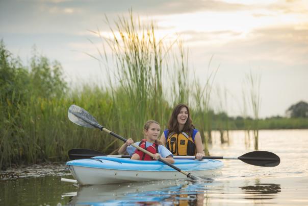 One adult and one child paddling on a kayak.
