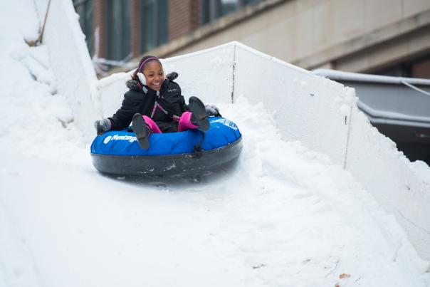 Young girl snow tubing down a snowy hill