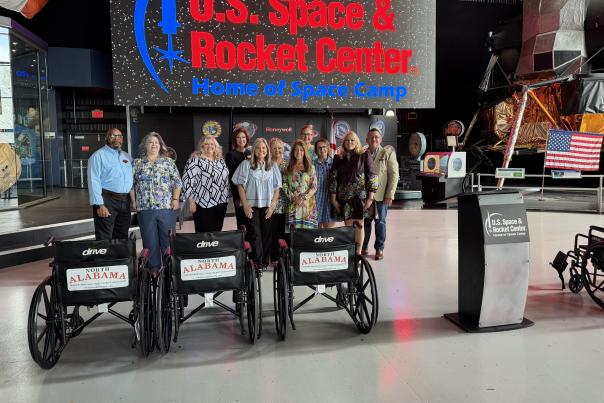 Staff members pose behind wheel chairs donated by AMLA to the U.S. Space and Rocket Center.