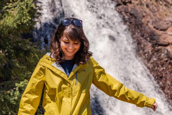 Woman with yellow coat in front of waterfall