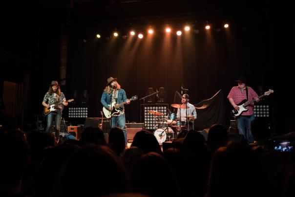Male band performing with instruments in front of crowd