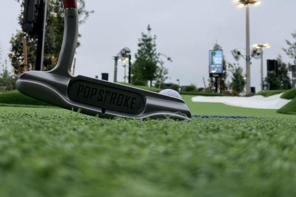 PopStroke Putter close up on the green, putter lined up against a golf ball, ready to hit it down the green