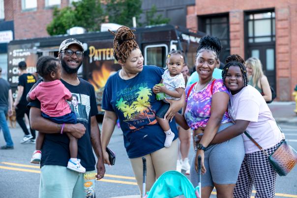 African-American family with three children, parents, and grandmother smiling at local festival