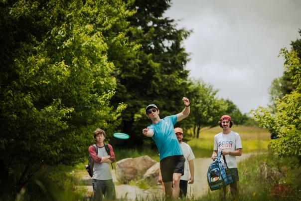 A disc golfer prepares to throw a disc with some friends behind them.