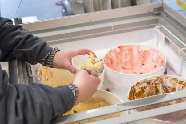 Hands scoop up ice cream into a dish