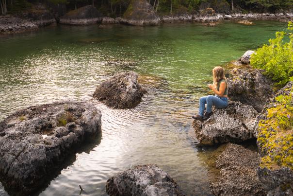 A woman sitting on a rock at the Les Cheneaux Islands, located in the Upper Peninsula