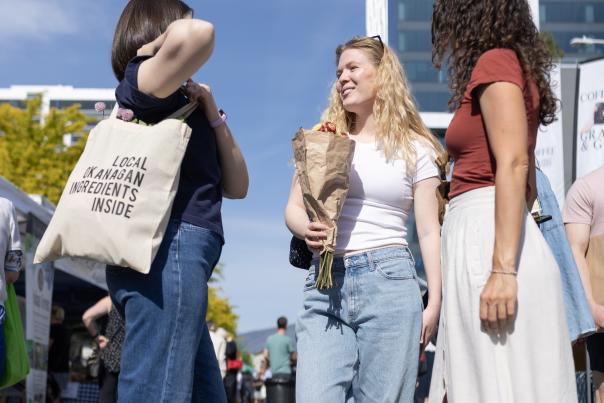 Three_Women_Chatting_in_the_Sunshine_at_Farmers_Market_with_Flowers_and_Tote_Bags