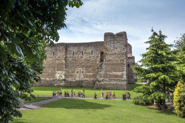 Colchester Castle photographed from a distance. A group of school children can be seen walking in front of it.