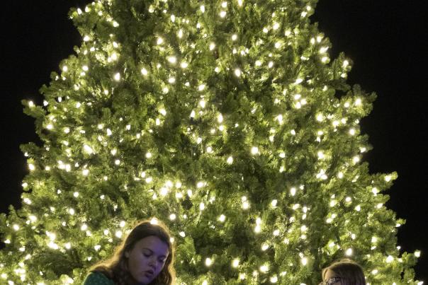 Mom and son sitting in front of town Christmas Tree