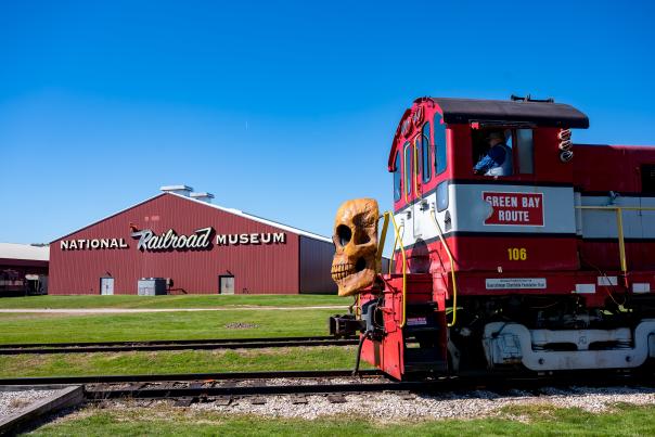 Train decorated for Halloween on its tracks in the foreground with a building that says National Railroad Museum in the background.