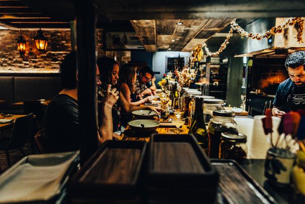 Image of diners sitting at the bar looking into the kitchen while eating their meals.
