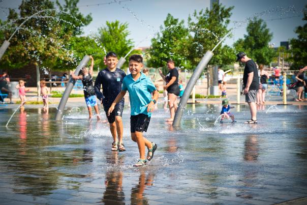 Kids running around the splash pad at Scissortail Park