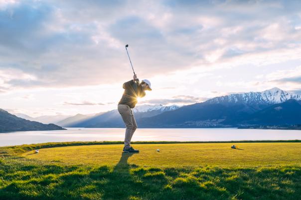 Man golfing with lake and mountain views