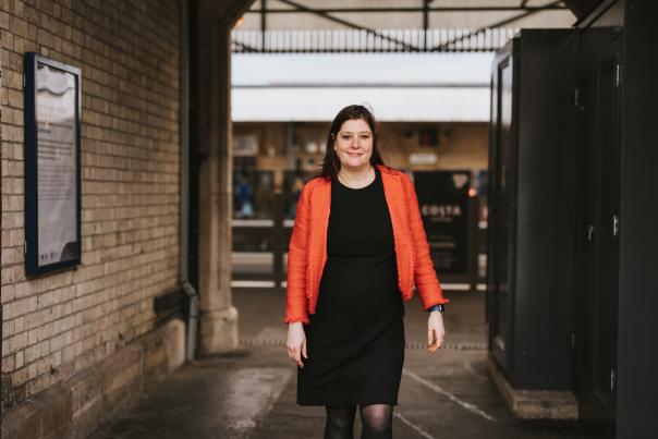 A woman in a red jacket walking through Lincoln train station