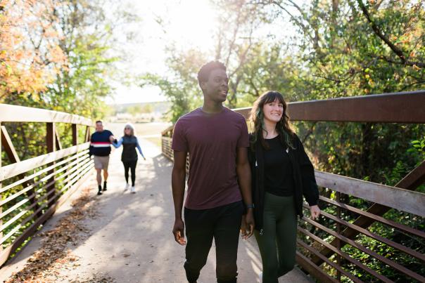 Two couples walking across a bridge hand-in-hand