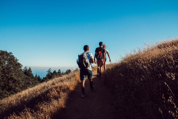 Group of teenagers hiking a trail with backpacks