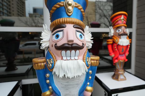 A classic nutcracker statue in a blue uniform with another nutcracker in red in the background