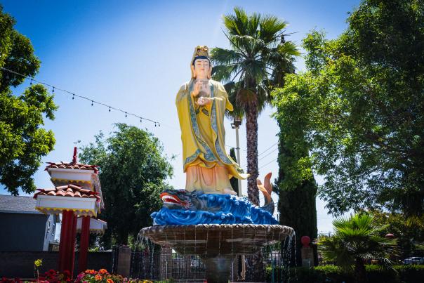 An outdoor statue of Buddha surrounded by greenery