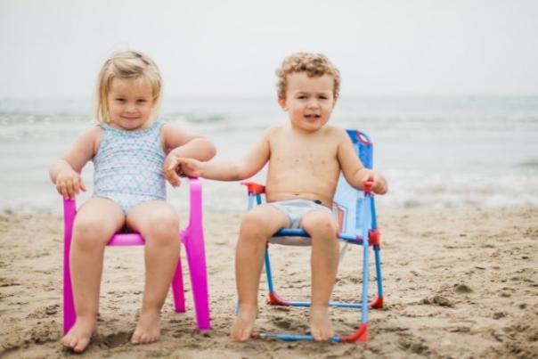 two children sat on chairs on the beach