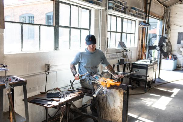 Man is torching a handmade piece of glass that is to be made into a bowl