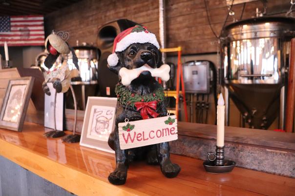 A dog statue with a santa hat and welcome sign inside of Black Paws Brewing Company in Devils Lake, ND.