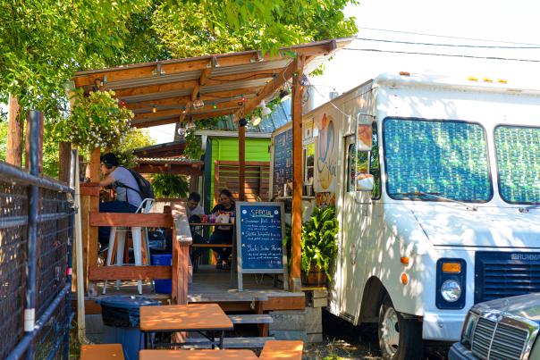 A food truck and shady porch for dining.