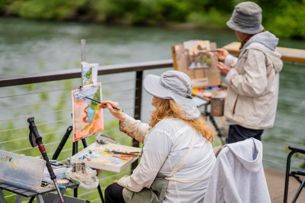 Two plein air artists over look the Willamette River with their painting set ups.