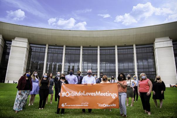 The Visit Orlando team holding a #OrlandoLovesMeetings banner in front of the Orange County Convention Center for Global Meetings Industry Day