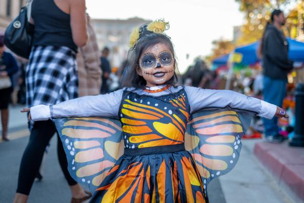 Child with day of the dead makeup sugar skull and monarch butterfly dress