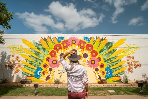 Photo of person standing in front of mural painted with colorful flowers