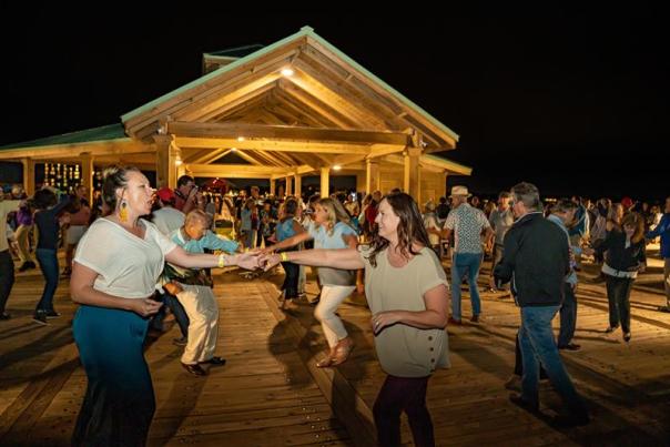 Group of people dancing on the Folly Beach Pier for the Moonlight Mixer series event.