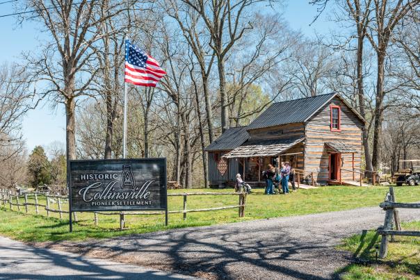 people outside of a historic log cabin