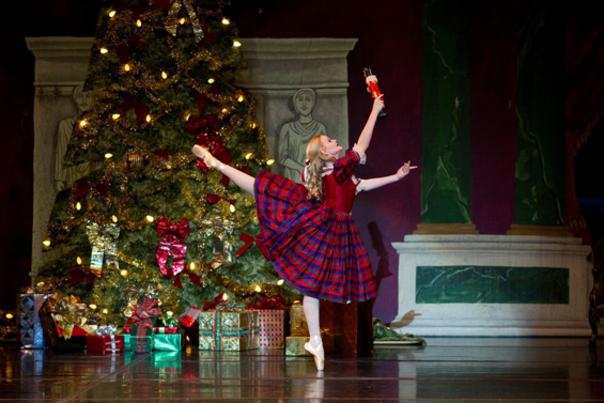 ballerina in a plaid dress posing in front of a Christmas tree
