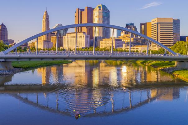 Downtown skyline featuring bridge over Scioto River and person kayaking in the river