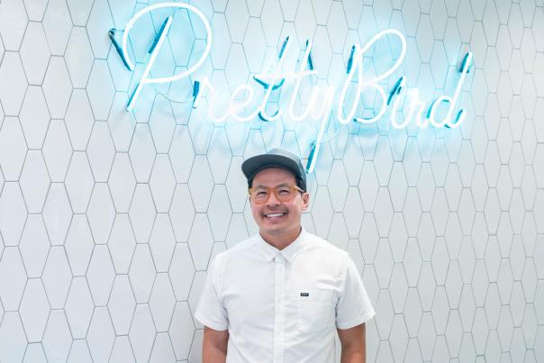 Viet Pham in front of the Pretty Bird sign
