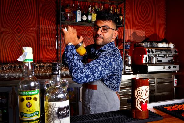 A bartender making a drink at a tiki bar